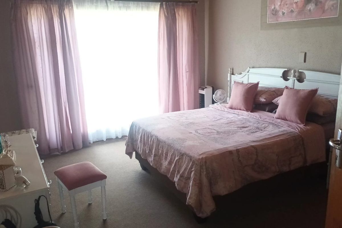 A standard bedroom featuring carpeted flooring and large windows with curtain tracks, offering a functional space with neutral wall finishes.