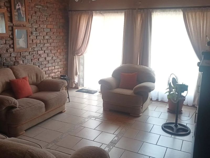 Living room featuring an exposed brick wall, ceramic tiled flooring, and large sliding glass doors providing natural light.