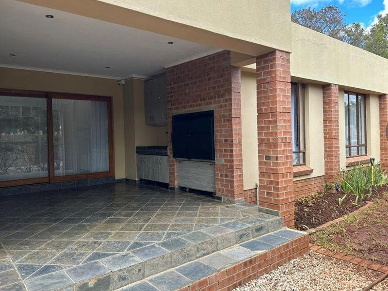 Covered patio area featuring a built-in braai, tiled flooring, and brick pillar accents, providing a functional outdoor entertainment space.
