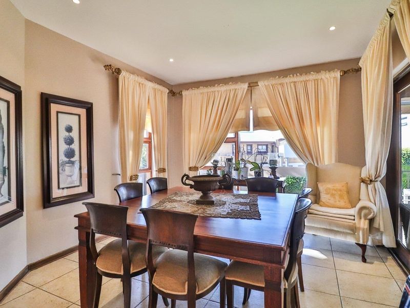 A well-maintained dining room featuring tiled flooring, recessed downlighting, and a sliding glass door providing access to the outdoor area.