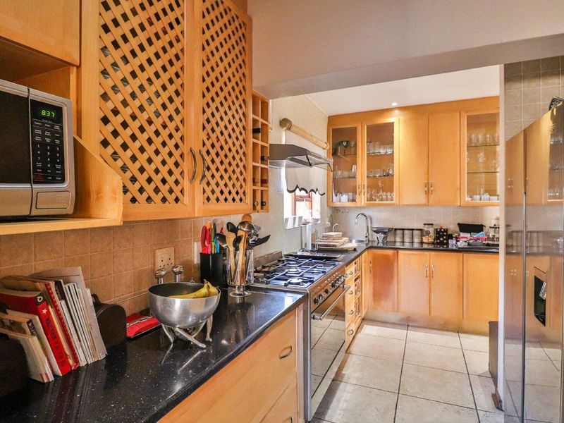 A functional kitchen featuring light wood cabinetry, granite countertops, a gas stove, and tiled flooring, offering a classic layout with ample storage space.