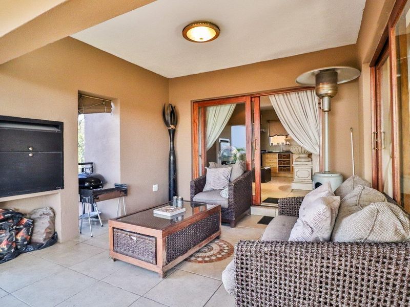 Covered patio area featuring a built-in braai, tiled flooring, and sliding glass doors providing access to the interior living space.
