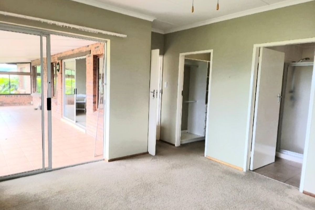 Spacious bedroom featuring neutral walls, carpeted flooring, a ceiling fan, and direct access to an en-suite bathroom and an outdoor patio area.