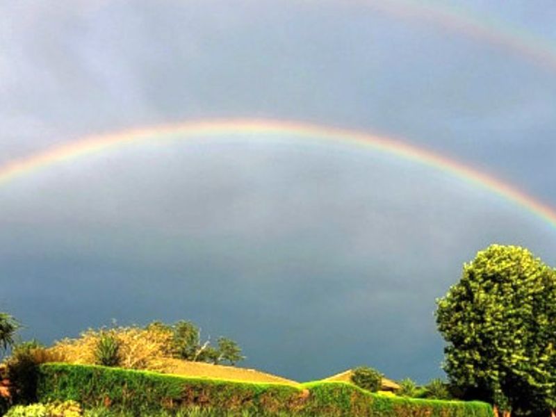 A scenic view of a double rainbow over the property's exterior roofline and garden area.