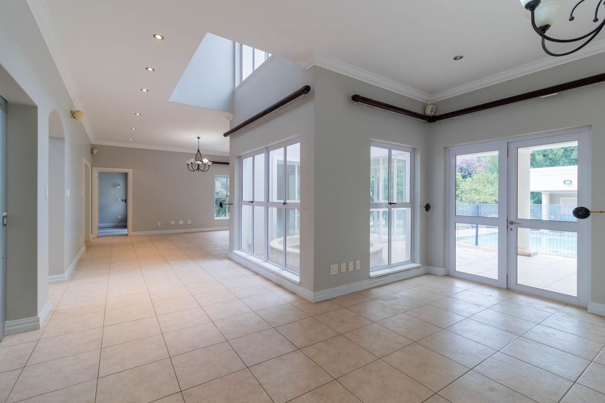 Spacious, light-filled living area featuring neutral tiled flooring, recessed lighting, a skylight, and direct access to the outdoor pool area.