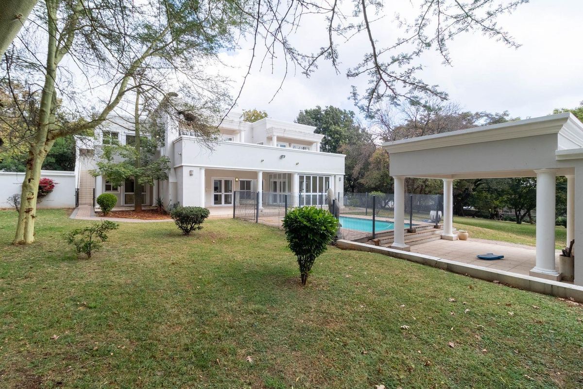 Rear view of the property featuring a swimming pool, covered patio with classical columns, and a spacious landscaped garden.