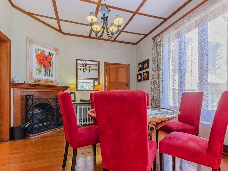 A dining room featuring a brick fireplace, timber flooring, and a decorative coffered ceiling, providing a classic and warm atmosphere.