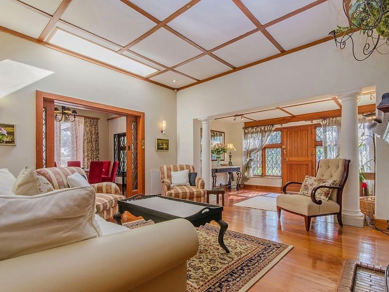 Spacious living room featuring polished hardwood floors, a coffered ceiling, a fireplace, and classic leaded glass windows, creating a warm and inviting atmosphere.