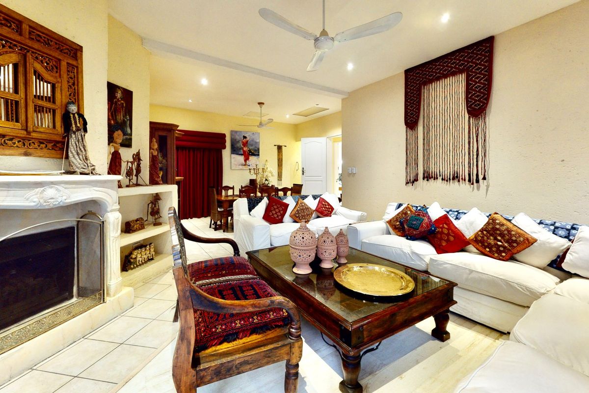 Spacious open-plan living and dining area featuring a classic fireplace, tiled flooring, and ceiling fans, offering a comfortable and versatile layout.