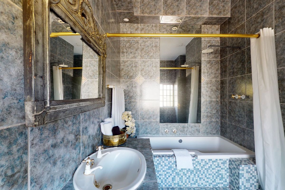 A bathroom featuring a built-in bathtub with shower, vanity basin, and decorative tiled wall finishes.