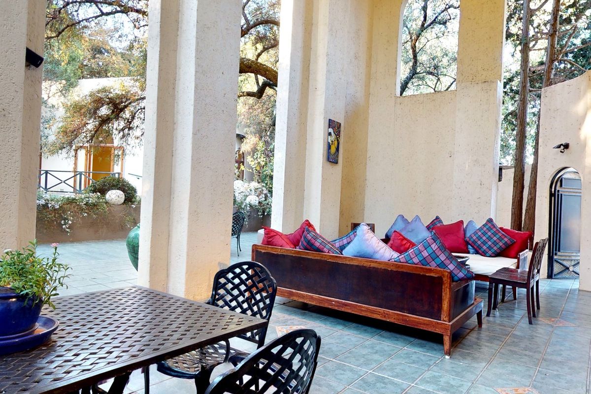 A spacious covered patio area featuring tiled flooring, structural pillars, and arched architectural details, providing a comfortable outdoor living space.