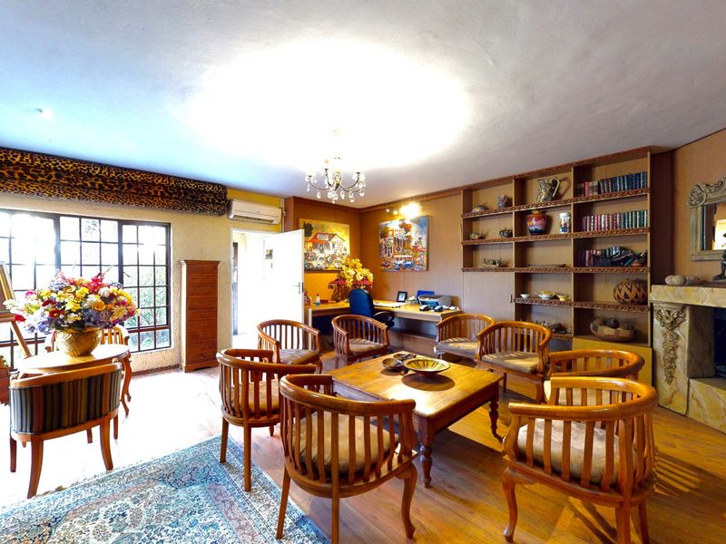 Spacious living room featuring timber flooring, a built-in fireplace, custom shelving, and large multi-pane windows providing natural light.