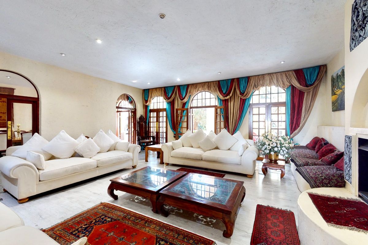 Spacious living room featuring arched doorways, tiled flooring, recessed lighting, and a built-in fireplace, with direct access to outdoor areas through french doors.