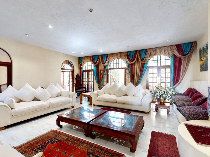 Spacious living room featuring arched doorways, tiled flooring, recessed lighting, and a built-in fireplace, with direct access to outdoor areas through french doors.