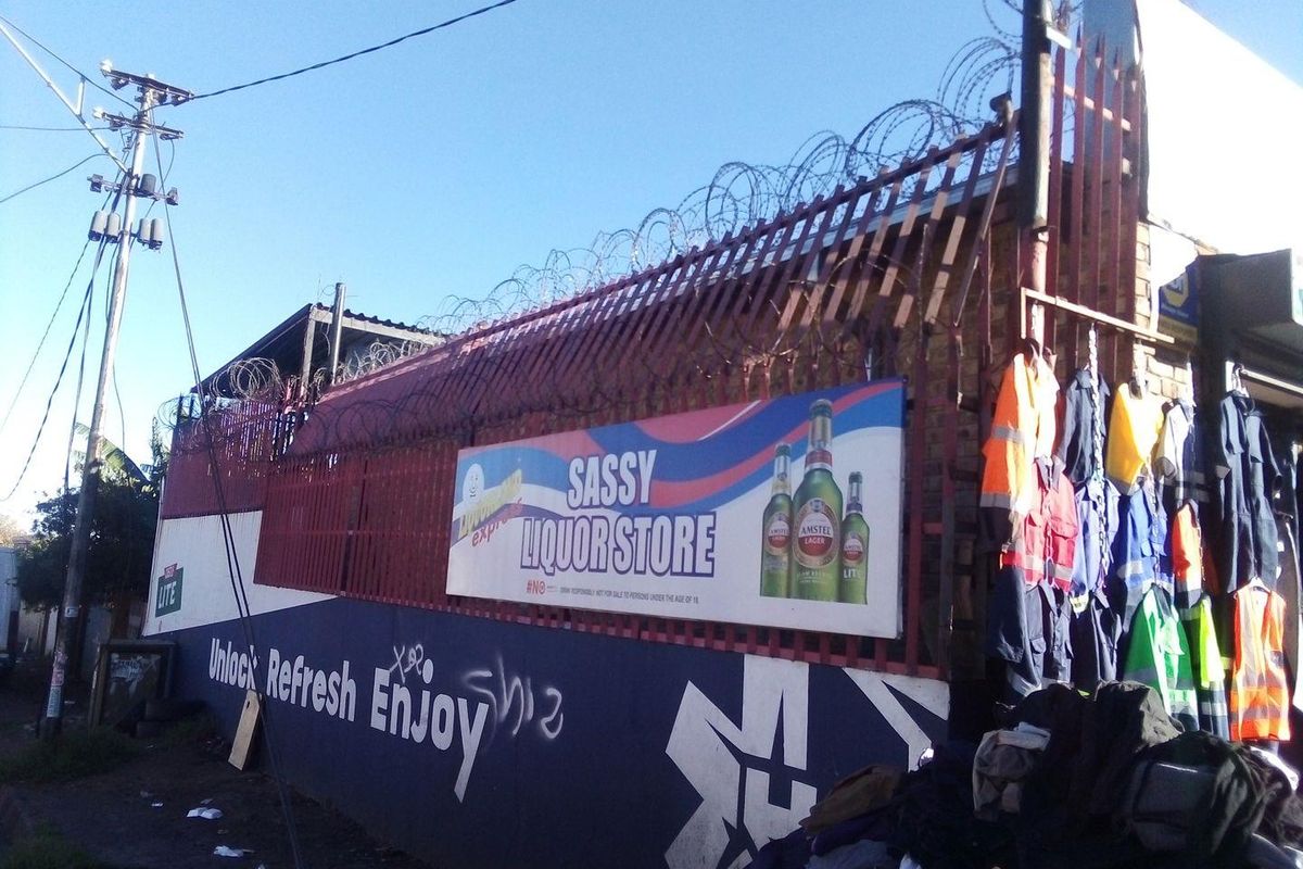 Exterior view of a commercial property featuring a brick wall with razor wire security fencing and prominent commercial signage.