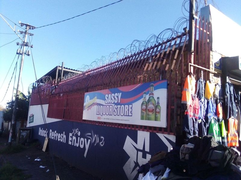 Exterior view of a commercial property featuring a brick wall with razor wire security fencing and prominent commercial signage.