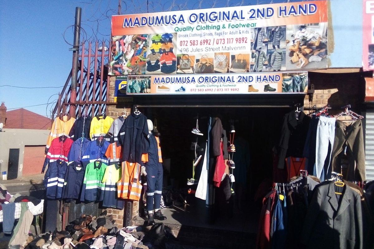 Front facade of a commercial retail unit featuring prominent signage and security fencing with razor wire.