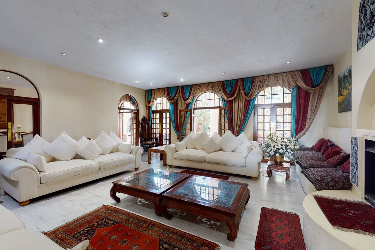 Spacious living room featuring a built-in fireplace, arched architectural details, tiled flooring, and multiple sets of French doors providing natural light.