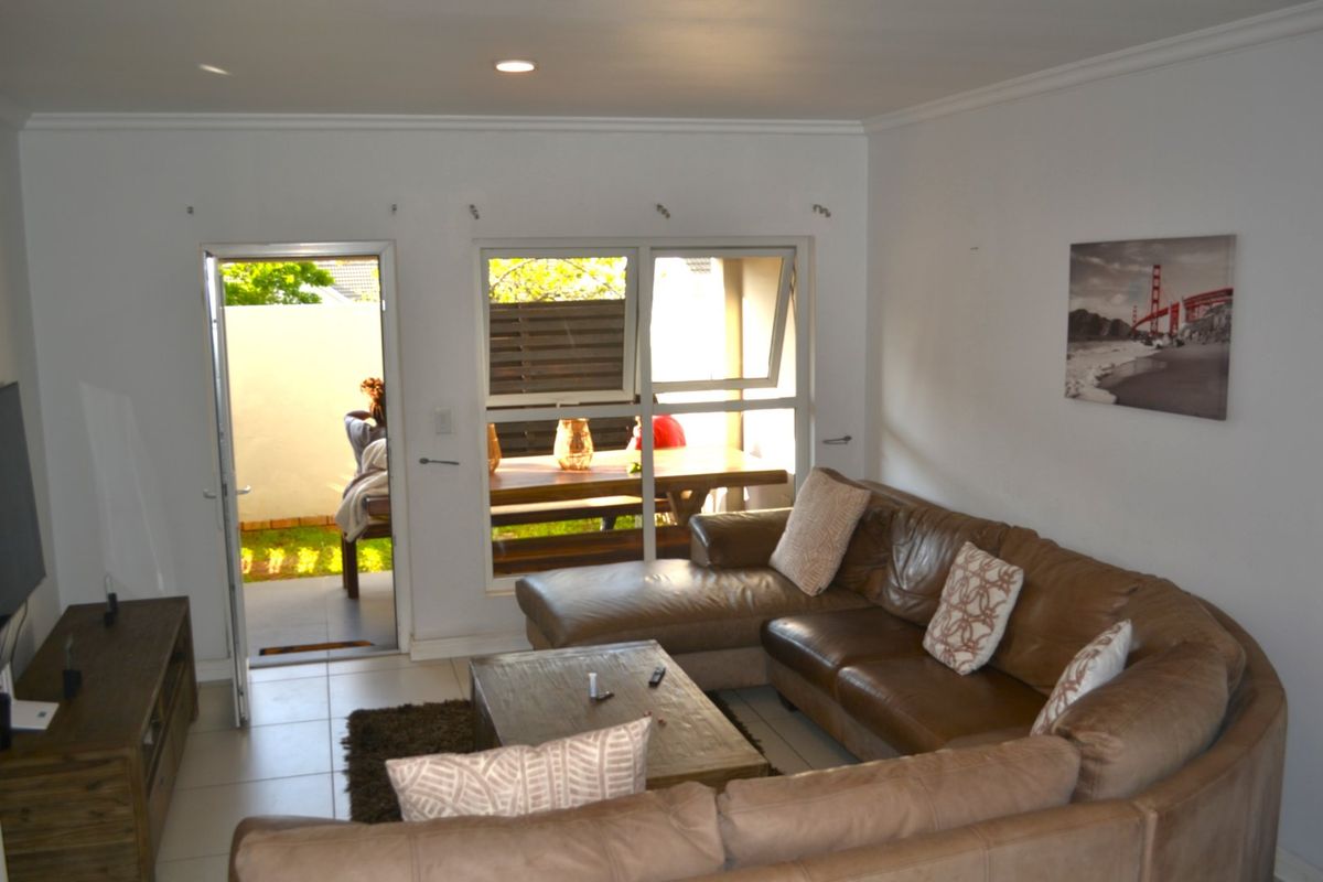 A bright living room featuring tiled flooring, recessed lighting, and direct access to an outdoor patio area through a glass door.