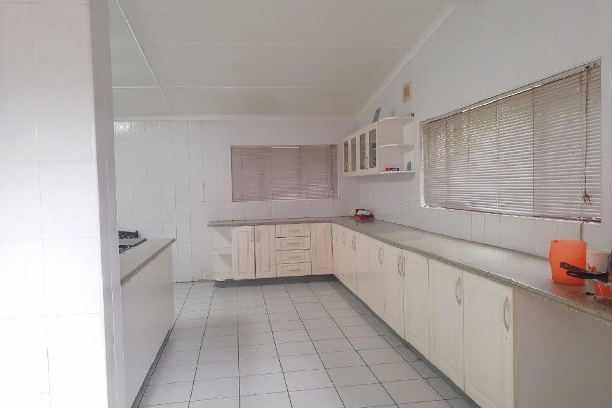 Spacious kitchen featuring extensive built-in cabinetry, stone countertops, and tiled flooring, offering a functional layout ready for modern updates.