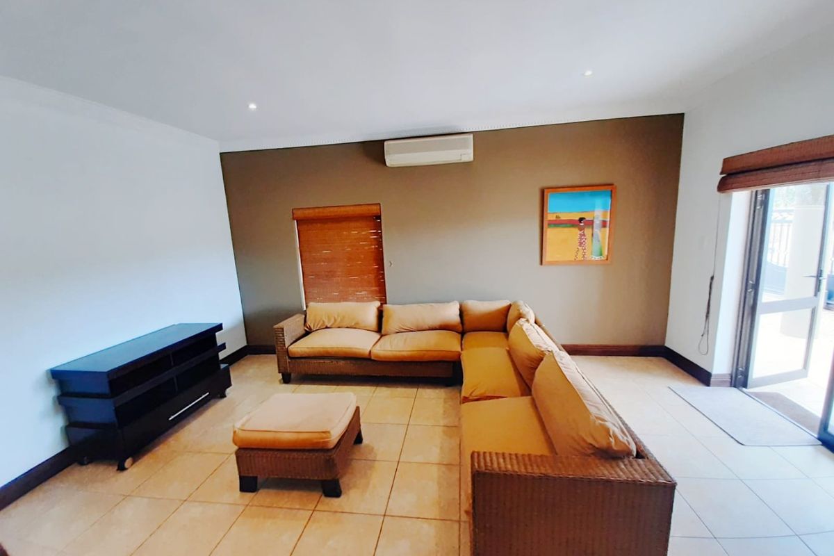 A spacious living room featuring tiled flooring, recessed lighting, an integrated air conditioning unit, and direct access to an outdoor area via a sliding door.