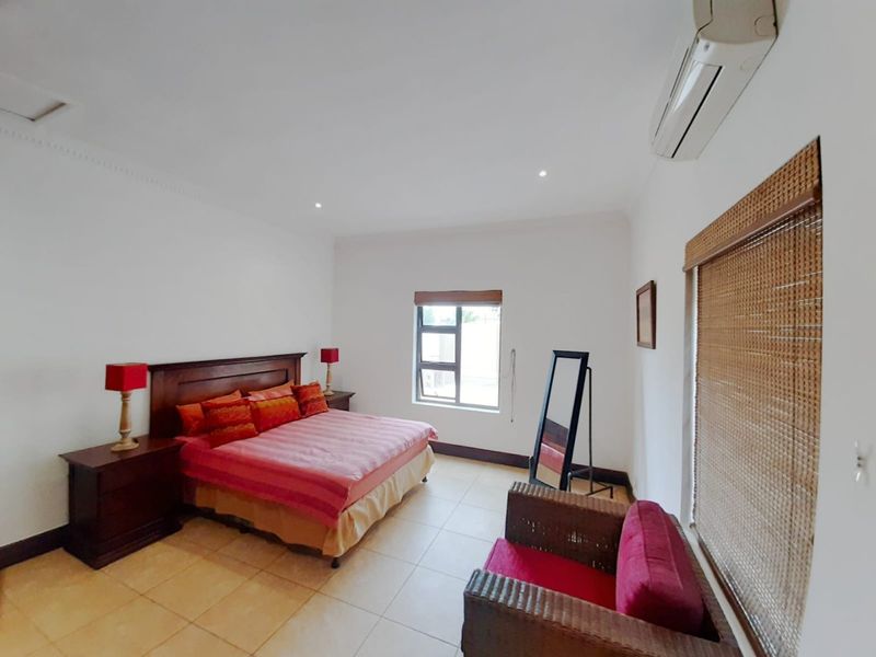 Spacious bedroom featuring tiled flooring, recessed lighting, and a wall-mounted split-system air conditioner for climate control.
