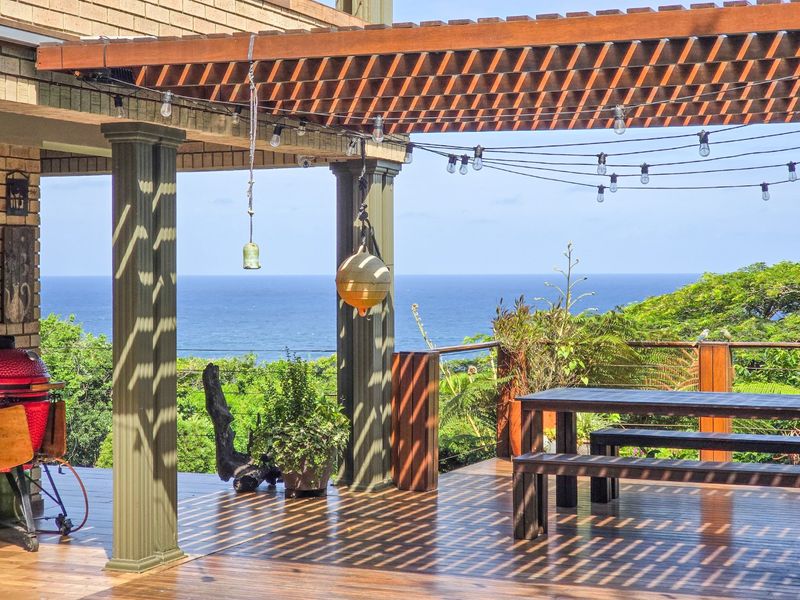 A spacious timber deck featuring a pergola, decorative columns, and cable balustrade, offering expansive ocean views and an ideal setting for outdoor entertaining.