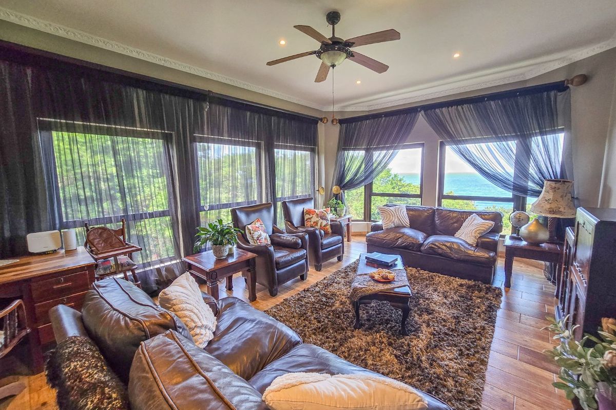 Spacious living room featuring tiled flooring, crown molding, recessed lighting, a ceiling fan, and large windows offering scenic ocean views.