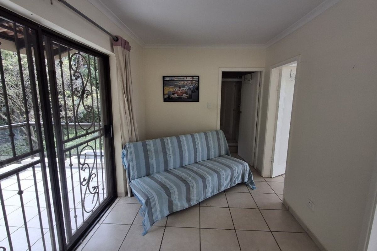 A living area featuring ceramic floor tiles, coved ceilings, and a sliding glass door with a security gate leading to an outdoor space.