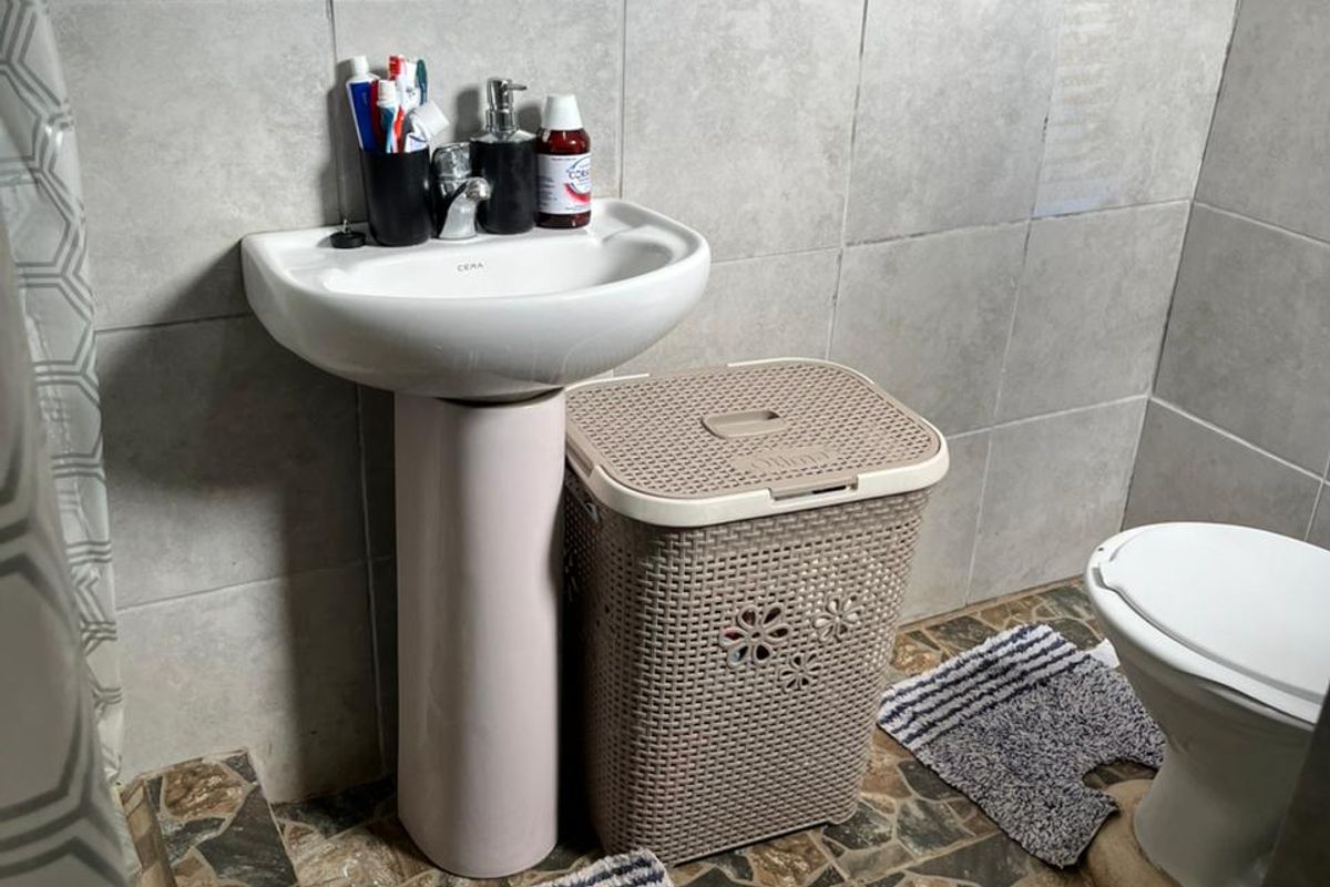 A compact bathroom featuring a pedestal basin, toilet, and decorative wall tiling with a patterned accent border.