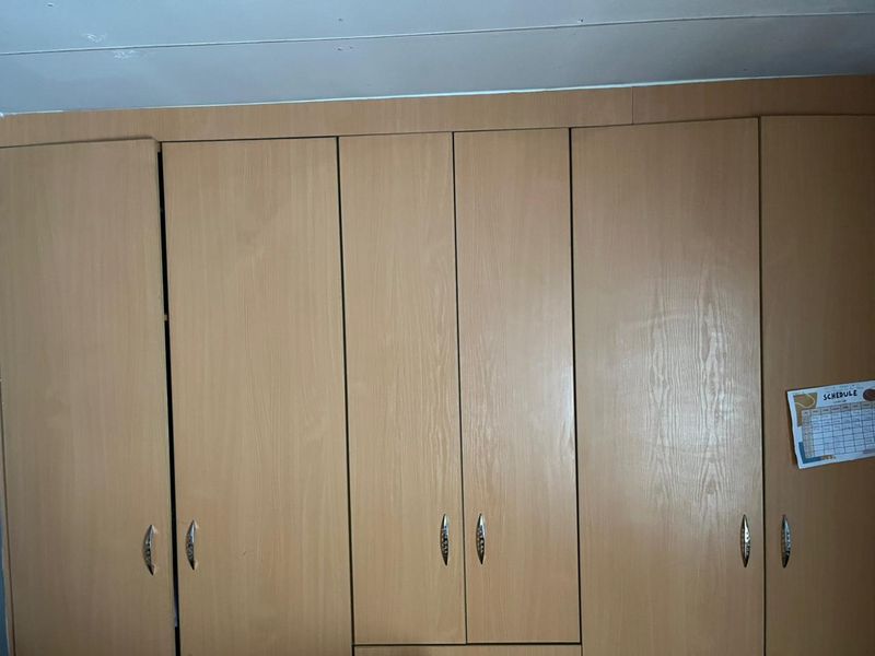 A bedroom featuring floor-to-ceiling built-in wooden cupboards with integrated handles.