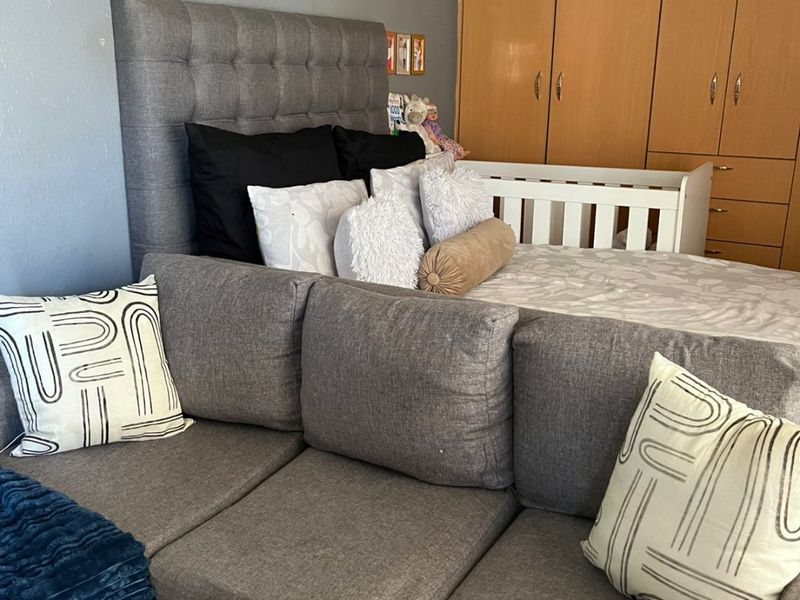A bedroom featuring built-in wooden cupboards and grey wall finishes, providing functional storage space within the room.