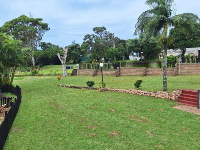 A well-maintained garden area featuring tiered lawn sections, stone-clad retaining walls, and brick steps leading to an outdoor space.