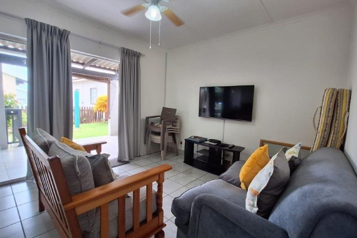 A functional living room featuring tiled flooring, a ceiling fan, and direct access to an outdoor patio area through sliding glass doors.