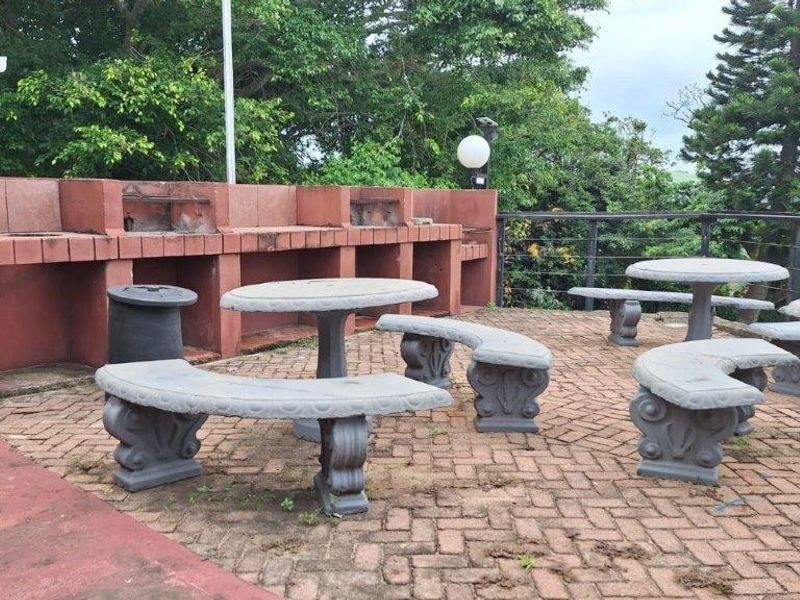 Outdoor patio area featuring a built-in brick braai, paved flooring, and metal safety railings, offering a functional space for outdoor entertaining.