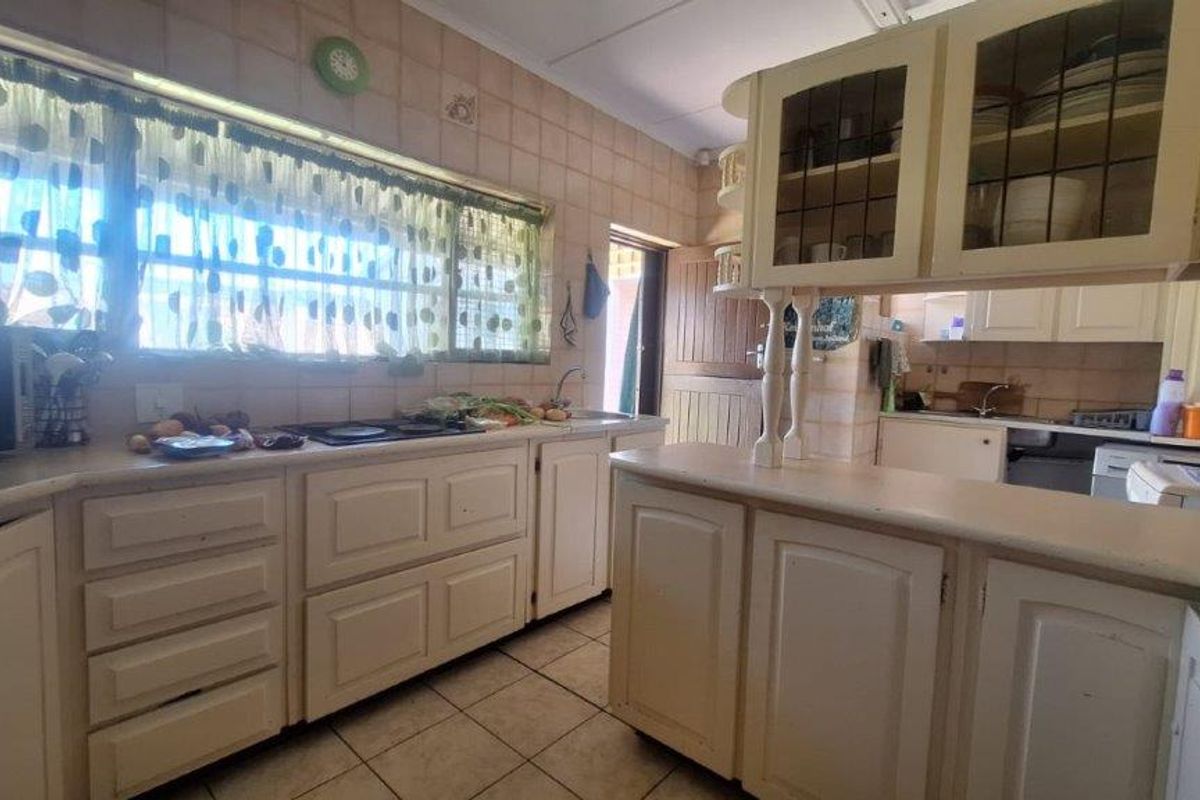 A functional kitchen featuring traditional built-in cabinetry, tiled backsplash, and a breakfast counter, offering a classic layout with potential for modern updates.