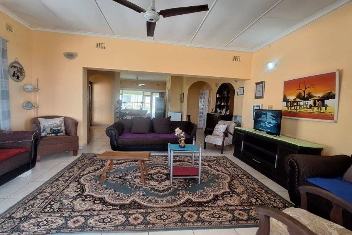 Spacious living room featuring tiled flooring, a ceiling fan, and an open-plan layout leading to an adjacent area through a classic archway.