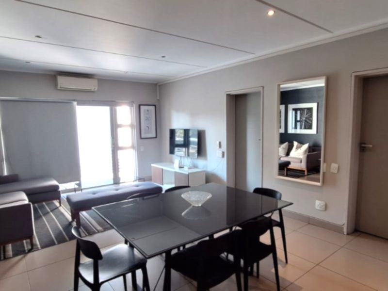 An open-plan living and dining area featuring tiled flooring, a split-system air conditioner, and a sliding glass door leading to an outdoor space.