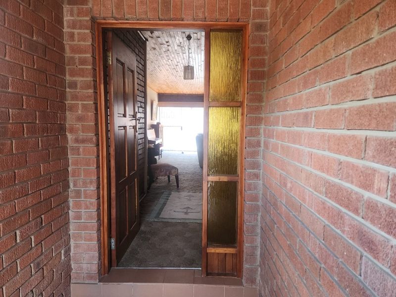 Entrance area featuring exposed brickwork and a classic timber door with a textured glass sidelight, providing a view into the interior living space.