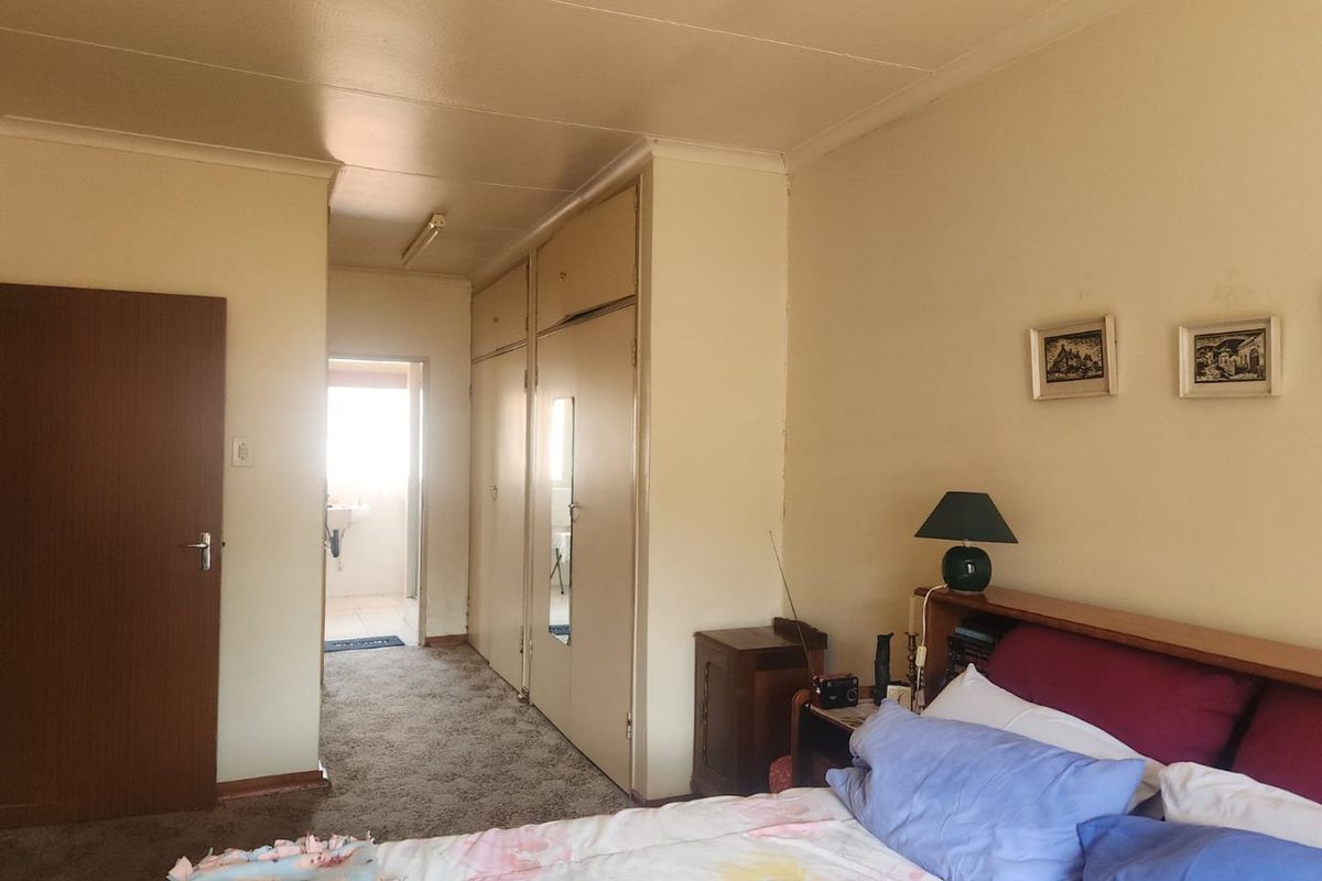 A bedroom featuring built-in cupboards, carpeted flooring, and coved ceilings, with an adjoining en-suite bathroom visible through the doorway.