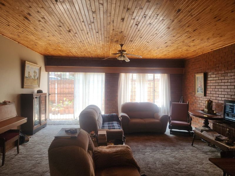Spacious living room featuring exposed brick walls, a timber-clad ceiling, and direct access to the exterior through a sliding glass door.