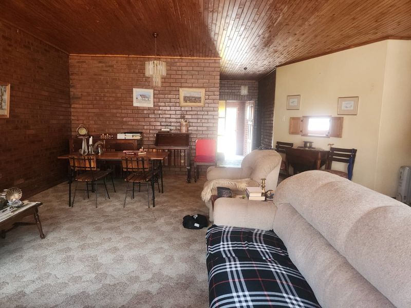 Spacious living area featuring exposed brick walls and a timber-clad ceiling, offering a rustic aesthetic with potential for modern updates.