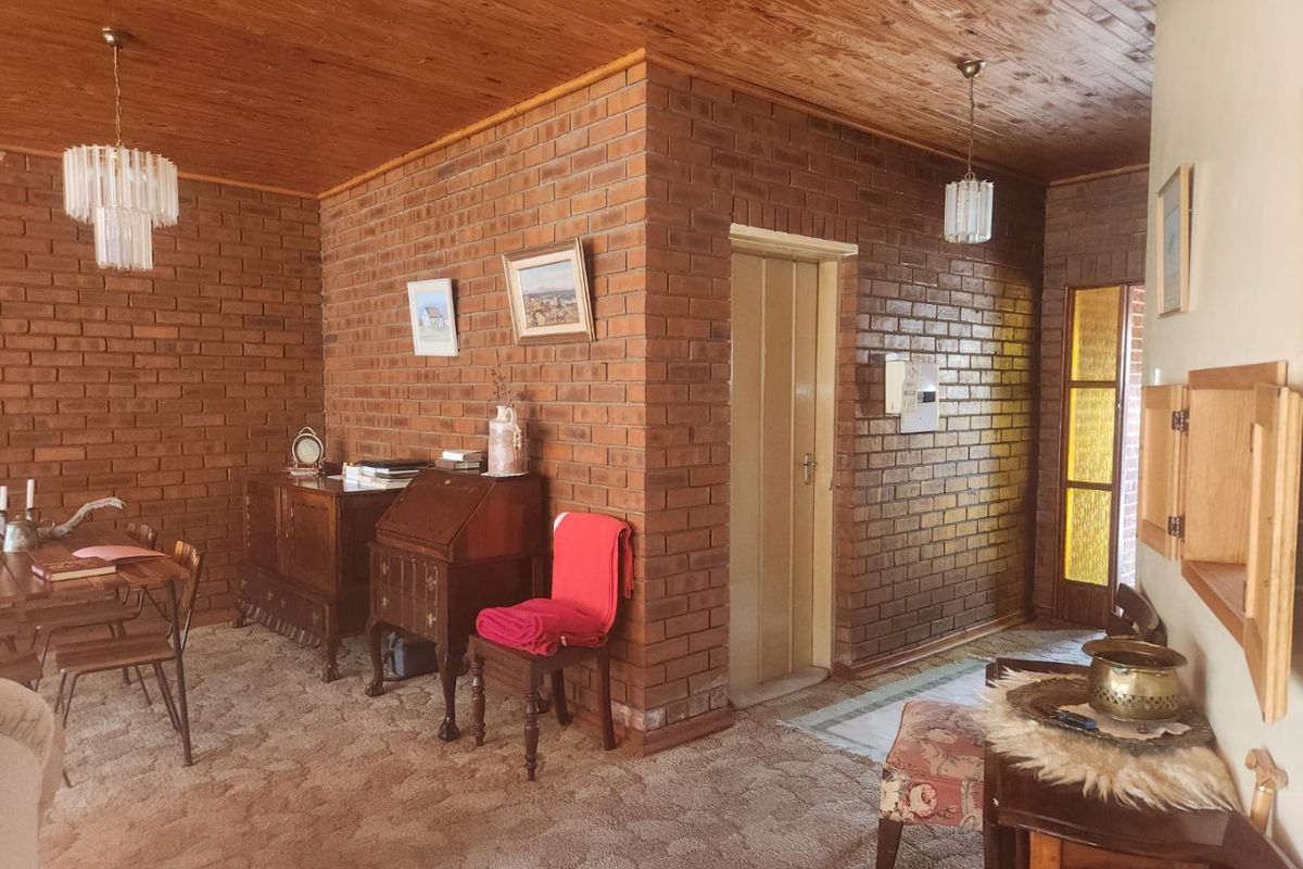 A living area featuring exposed brick walls, a timber ceiling, and classic pendant lighting, offering a rustic aesthetic with potential for modern updates.