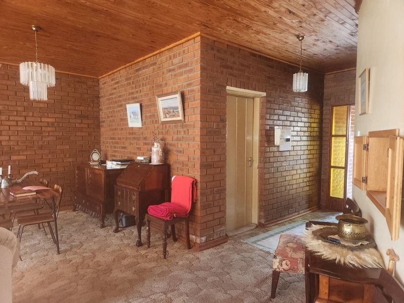 A living area featuring exposed brick walls, a timber ceiling, and classic pendant lighting, offering a rustic aesthetic with potential for modern updates.