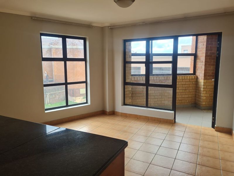 An open-plan living area featuring tiled flooring, a granite countertop, and direct access to a private balcony through a sliding door.