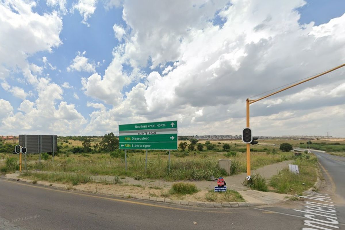 A view of the vacant residential land situated at a road intersection, featuring surrounding infrastructure and local signage.