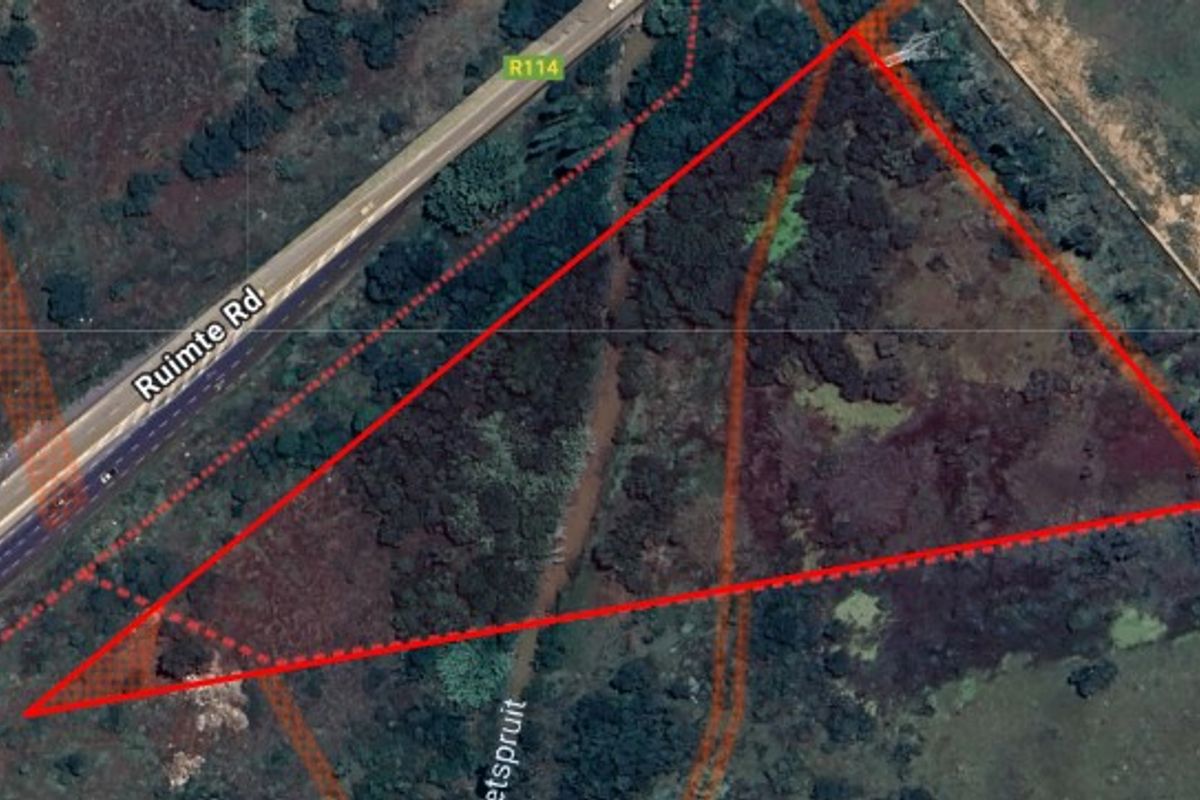 Aerial view of a vacant residential land parcel with road frontage, featuring natural vegetation and terrain.