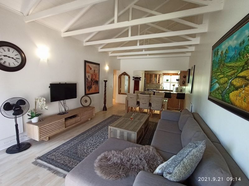 Open-plan living and dining area featuring a vaulted ceiling with exposed white timber trusses and integrated kitchen space with cabinetry.
