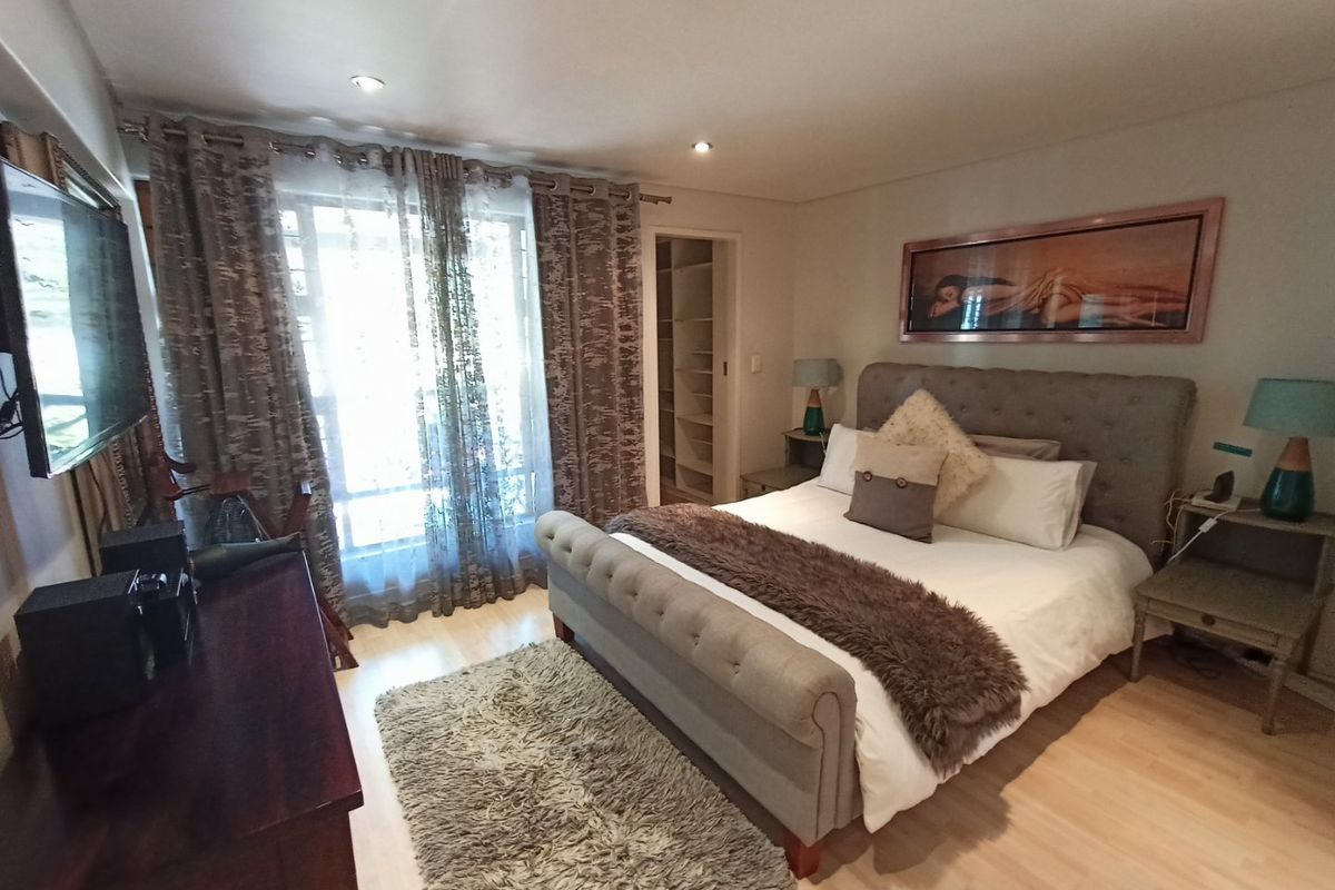 A well-maintained bedroom featuring laminate flooring, recessed downlighting, and integrated built-in shelving, offering a comfortable and functional living space.