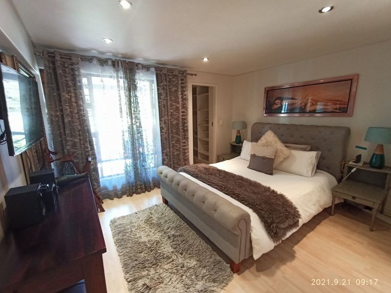 A well-maintained bedroom featuring laminate flooring, recessed downlighting, and integrated built-in shelving, offering a comfortable and functional living space.